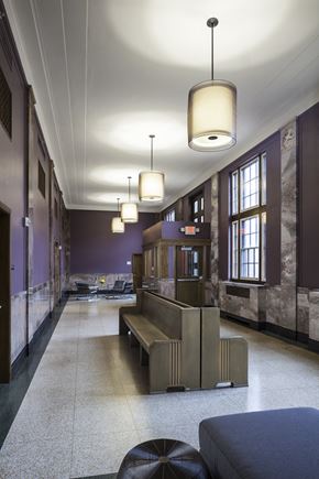 Wausau apartment for rent - A long hallway with a bench and lights hanging from the ceiling.