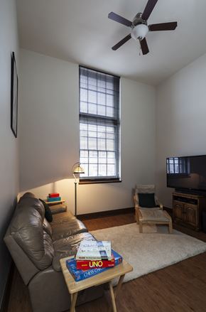 Wausau apartment for rent - A living room with a couch, a chair, a coffee table, a ceiling fan, and a television.