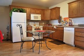Albert Lea townhouse for rent - A kitchen with a white fridge, a glass top stove, and wooden cabinets.