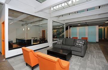 Wausau apartment for rent - A modern living room with a grey couch and orange chairs.