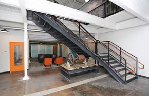 Wausau apartment for rent - A staircase with orange handrails leads to a room with a large orange door.