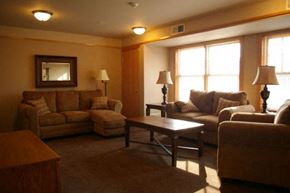 Osceola apartment for rent - A living room with a brown couch, a brown armchair, a brown chair, a brown coffee table, and a brown rug.