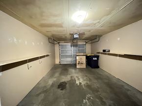 Ellsworth apartment for rent - A long, narrow, unfinished room with a concrete floor and ceiling, a metal door, and a cardboard box on the floor.