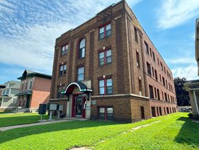 Winona apartment for rent - a tall brick building with a green lawn in front of it