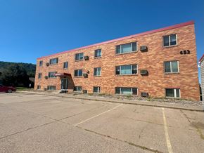Winona apartment for rent - A red brick building with a parking lot in front.