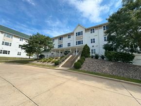 Cedar Rapids apartment for rent - A large white building with a green roof and a stone pathway leading to the entrance.