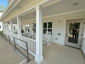 Cedar Rapids apartment for rent - A white porch with a metal railing and chairs.