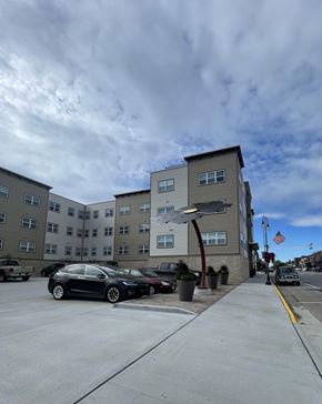 New Richmond apartment for rent - A black car is parked in a parking lot in front of a grey building.