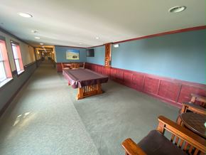Cedar Rapids apartment for rent - A long room with a pool table, chairs and a television on the wall.