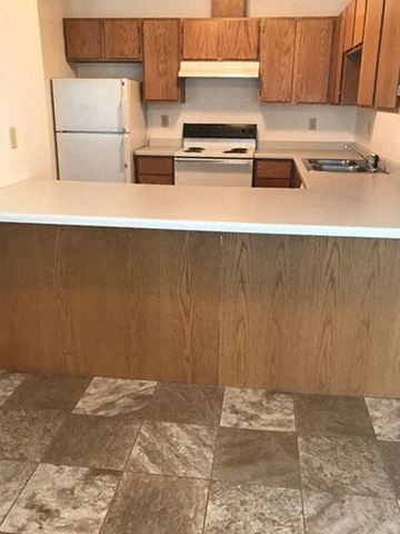 Chatfield apartment for rent - A kitchen with a white refrigerator and wooden cabinets.