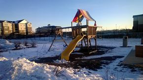 Ames apartment for rent - A playground with a yellow slide and a red and yellow umbrella.