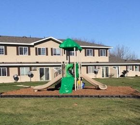Chatfield apartment for rent - A playground with a green slide in front of a building.
