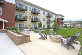 Rochester apartment for rent - A patio with chairs and a fire pit in front of a building.