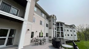 Winona apartment for rent - A white two-story apartment building with a balcony and patio furniture.