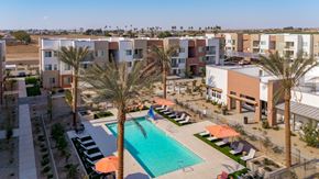 Buckeye apartment for rent - A swimming pool surrounded by palm trees and sun loungers in front of apartment buildings.