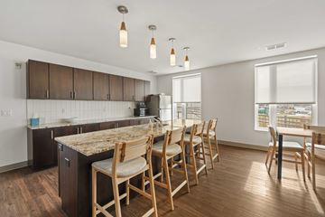 Sun Prairie apartment for rent - A kitchen with wooden chairs and a granite counter.