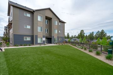 Flagstaff apartment for rent - A large grassy area in front of a grey apartment building.
