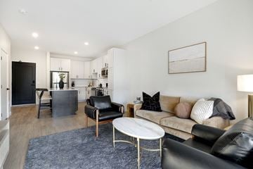 Shakopee apartment for rent - A living room with a black leather couch and a white coffee table.