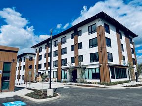 Tigard apartment for rent - a building with a parking lot in the foreground and a blue sky in the background