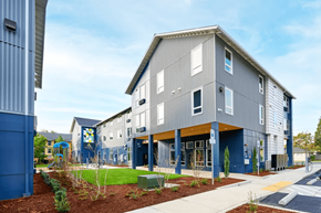 Portland apartment for rent - A modern building with a blue and grey exterior and a playground in front.