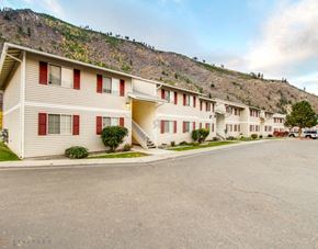Missoula apartment for rent - A row of identical apartments with red trim and a mountain in the background.