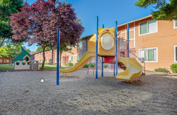 Forest Grove apartment for rent - a playground with a yellow swing set in front of a school building