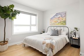 Saskatoon townhouse for rent - A bedroom with a large bed and a painting on the wall.