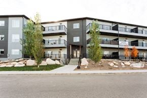 Saskatoon apartment for rent - Apartment building with a grey and black exterior and a balcony on the second floor.