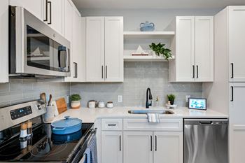 A kitchen with white cabinets and appliances and a sink