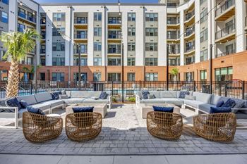 An outdoor lounge area with couches and chairs in front of an apartment building