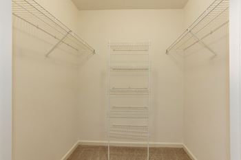 A walk in closet with four metal shelves in a white room