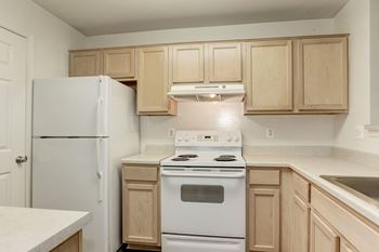 An empty kitchen with white appliances and wooden cabinets