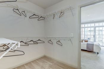 An image of a closet with hooks on the wall and a bed in the corner