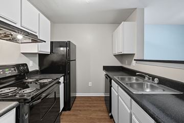 Lithonia apartment for rent - A black refrigerator sits in a kitchen with white cabinets.