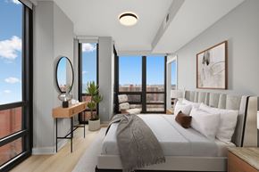 Washington apartment for rent - A modern bedroom with a large bed and a view of the city.