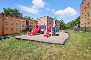 A playground with a red slide and a blue slide in the middle of a grassy area