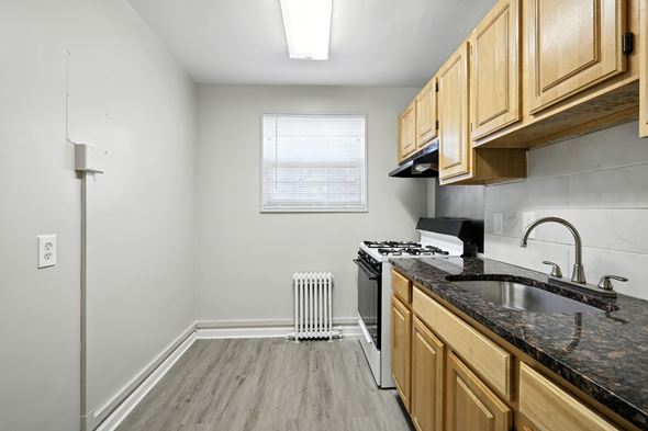 Washington apartment for rent - A kitchen with wooden cabinets and a black countertop at Huntwood Courts Apartments, Washington DC