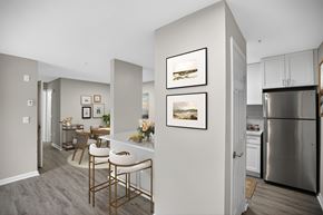 Lorton apartment for rent - A kitchen with a refrigerator, a dining table with chairs, and pictures on the wall.