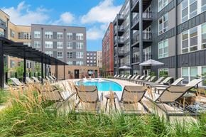 Reston apartment for rent - A pool surrounded by chairs and umbrellas in front of apartment buildings.