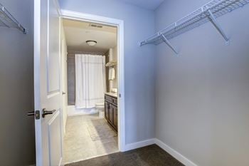 A walk in closet in a bathroom with a shower and a sink