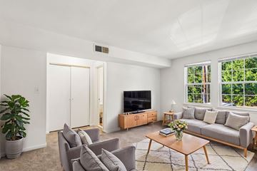 Chevy Chase apartment for rent - A living room with a grey couch, a wooden coffee table, and a flat screen TV.