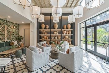 A lobby with chairs and a wall filled with vases