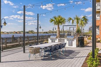A patio with a table and chairs and a bar and a body of water