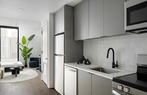 Tampa apartment for rent - A modern kitchen with white cabinets and a black stove top at Miles at Ybor Apartments, Tampa, FL