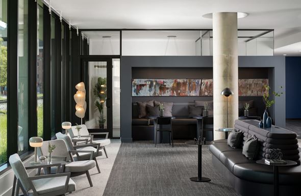 Tampa apartment for rent - A modern living room with a black couch and grey chairs at Miles at Ybor Apartments, Tampa, FL