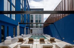 Tampa apartment for rent - A modern outdoor seating area with white furniture and a pool at Miles at Ybor Apartments, Tampa, Florida