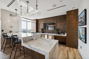 A kitchen with a marble counter top and a bar with stools