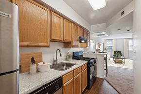 Chevy Chase apartment for rent - A kitchen with wooden cabinets and a stainless steel refrigerator at The Fields of Bethesda, Chevy Chase, MD