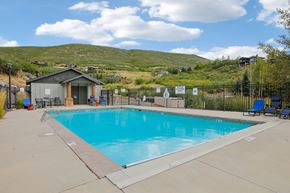 Hideout apartment for rent - A swimming pool surrounded by a fence with a mountain in the background.