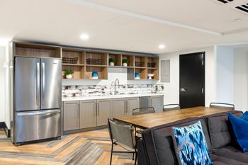 A modern kitchen with a refrigerator, sink, and bar area.